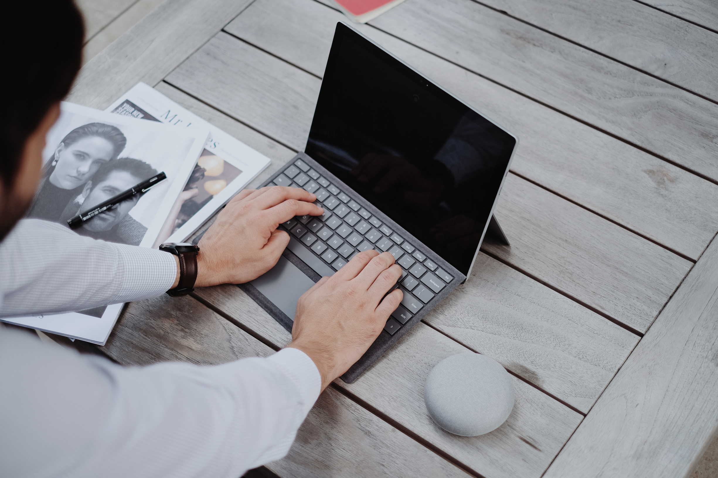 Man working on laptop beside magazines